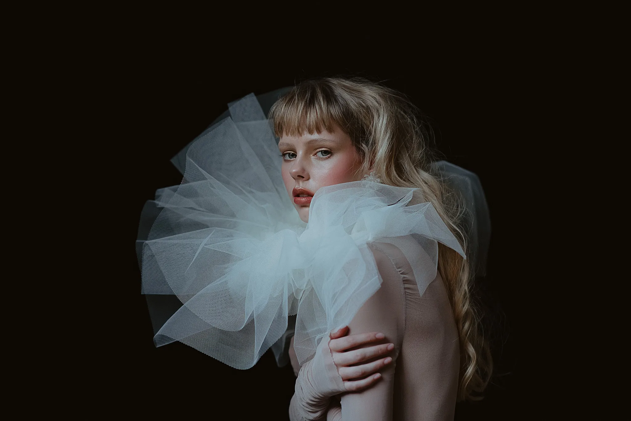 Model wearing a sculptural textile piece against a dark background