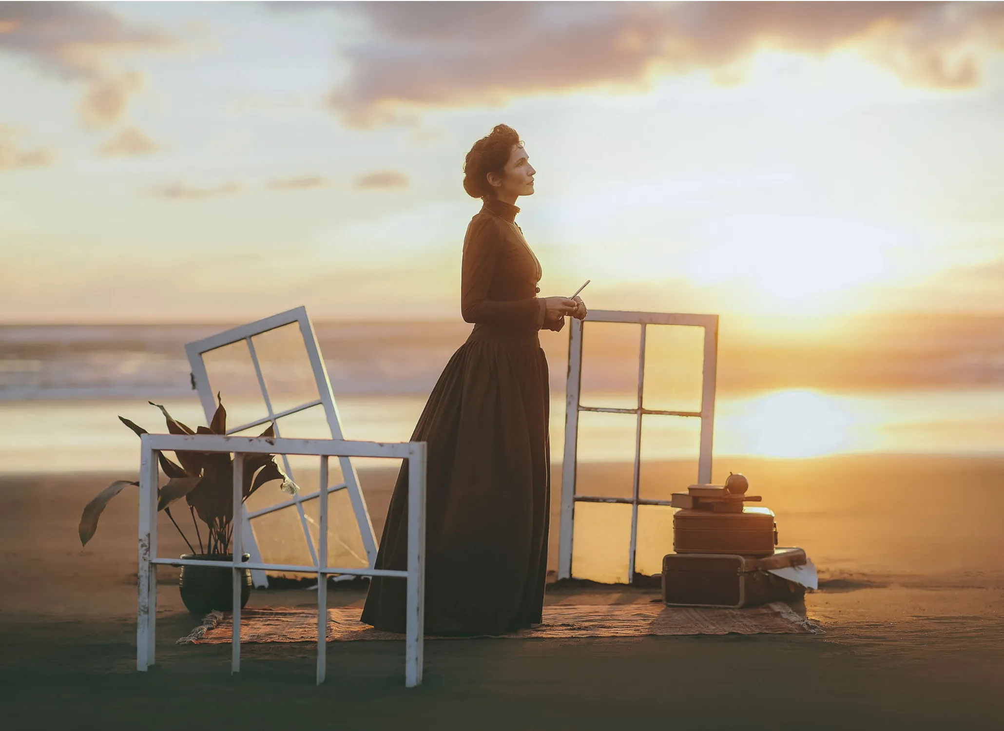 The same costume in silhouette between two window frames on a beach at sunset
