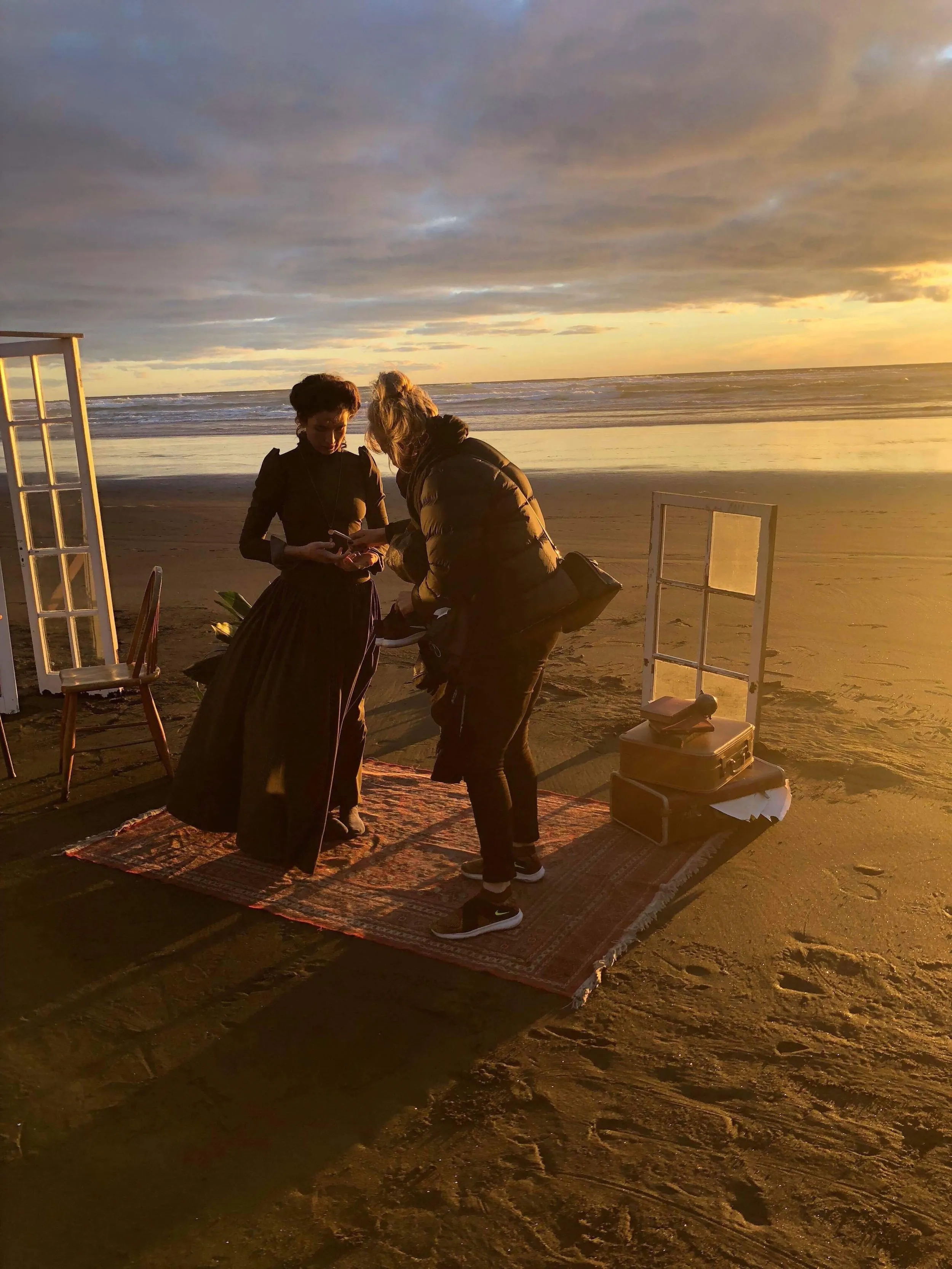 Behind the scenes on Piha beach at sunset, with a final costume check before the shoot